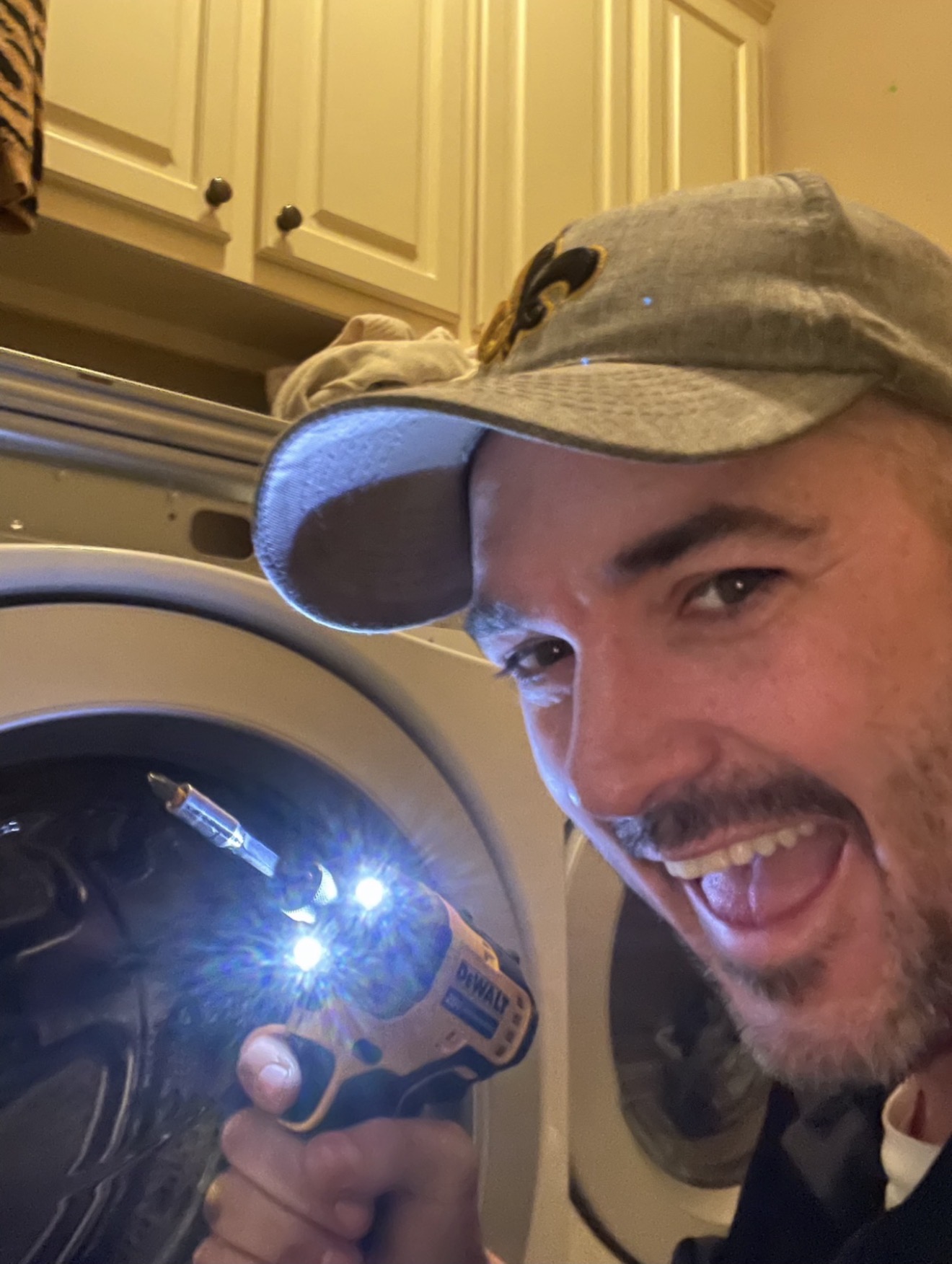 Johnny holding a drill beside an open front-loading washer